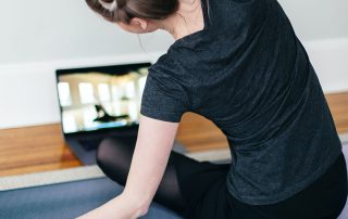 a decorative image showing a lady watching a yoga class on her laptop